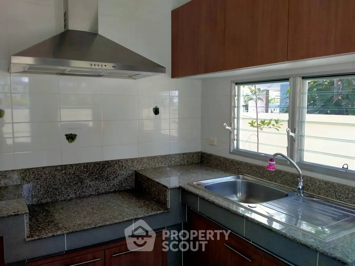 Modern kitchen with granite countertops and stainless steel range hood