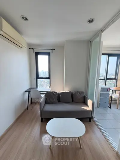 Modern living room with city view, featuring a cozy sofa and sleek furniture, perfect for urban living.