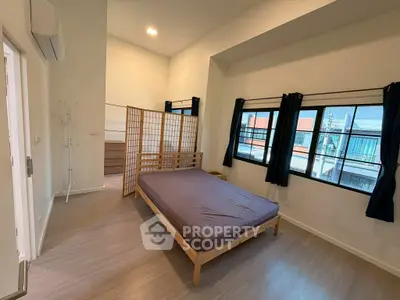 Spacious bedroom with large windows and modern decor in a stylish apartment.
