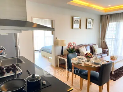 Modern open-layout living room with kitchen and dining area, featuring elegant decor and natural light.