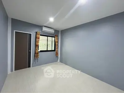 Spacious empty bedroom with air conditioning and large window, perfect for customization.