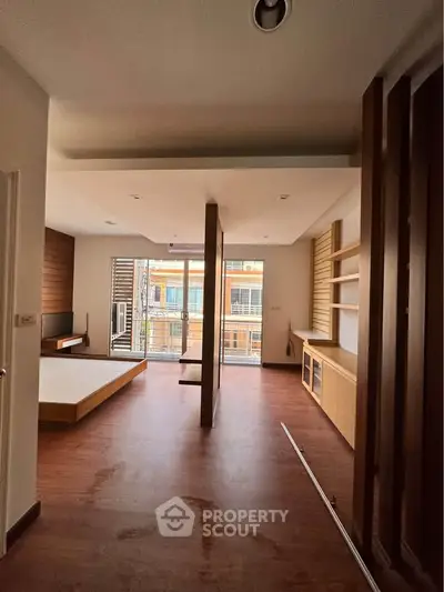 Spacious modern living room with wooden flooring and large windows for natural light.