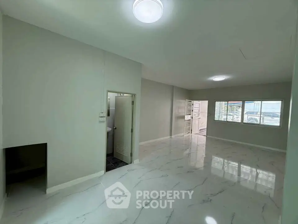 Spacious open-plan living area with marble flooring and ample natural light.