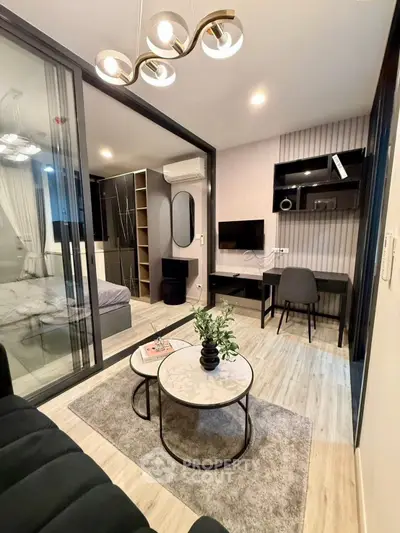 Modern living room with stylish decor and adjacent bedroom in open layout apartment.