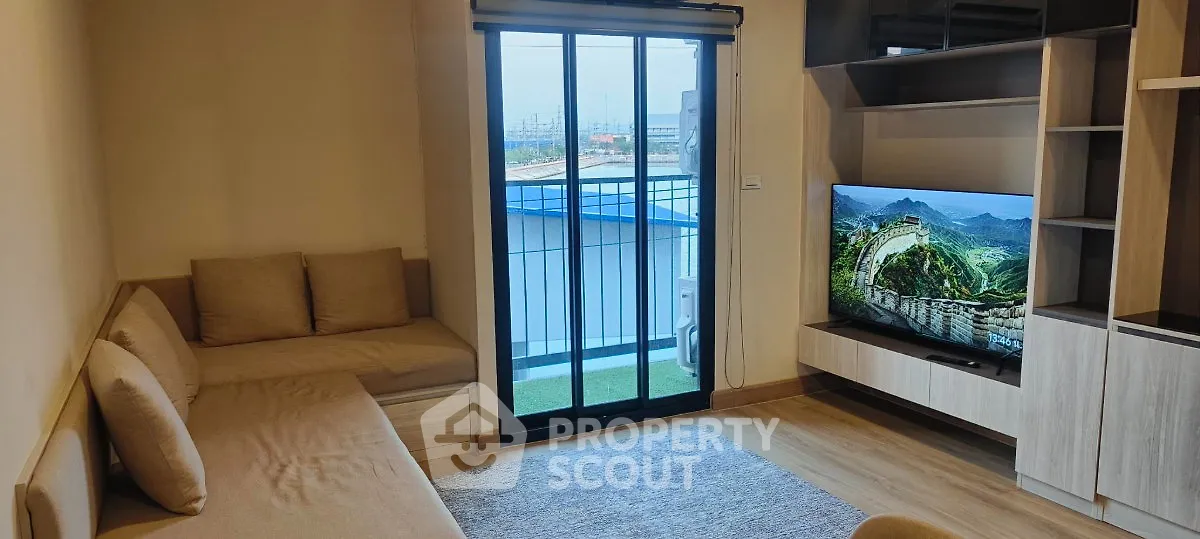 Modern living room with cozy seating and large TV, featuring a balcony view.