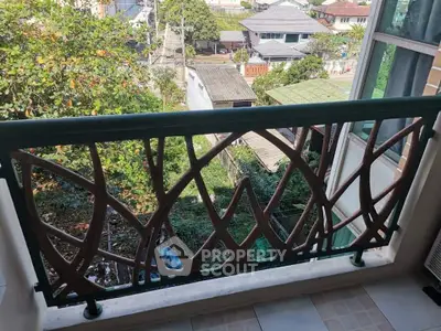 Charming balcony with artistic railing offering a lush green view in a serene neighborhood.
