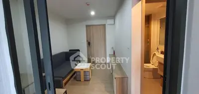 Modern apartment interior with cozy living room and adjacent bathroom view.