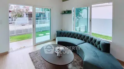 Spacious living room with modern curved sofa and large windows overlooking garden