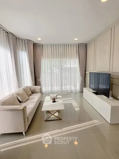 Elegant living room with modern decor, large windows, and natural light, perfect for relaxation and entertainment.