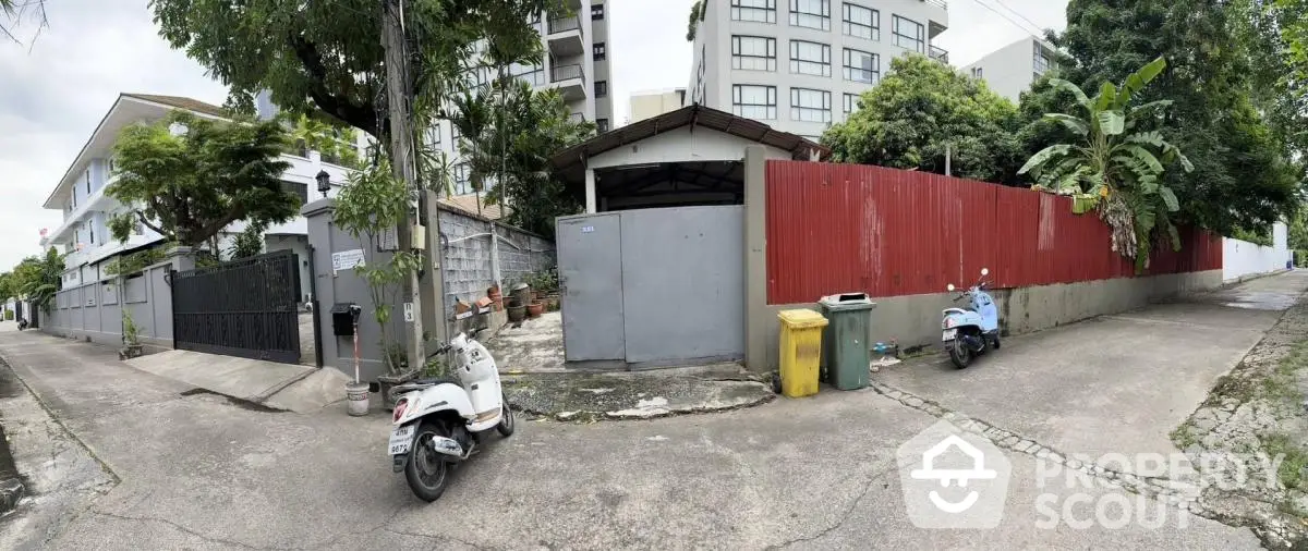 Charming urban alleyway with scooters, lush greenery, and modern apartment buildings, perfect for city living.