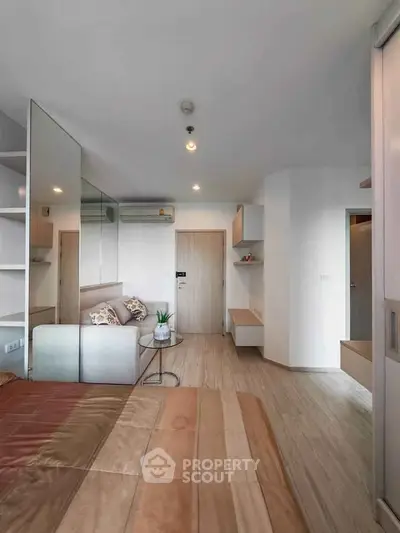 Modern bedroom with stylish decor and mirrored wall in a contemporary apartment.