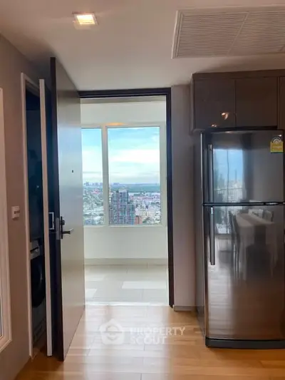 Modern kitchen with stainless steel fridge and stunning city view from the window.