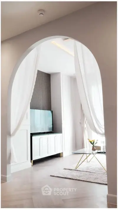 Elegant living room with modern decor and stylish archway, featuring a sleek TV setup and cozy ambiance.