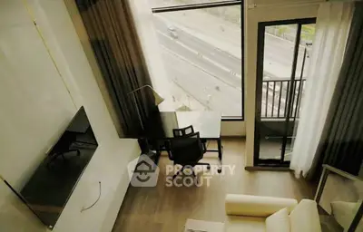 Modern living room with balcony and city view, featuring sleek furniture and large windows.