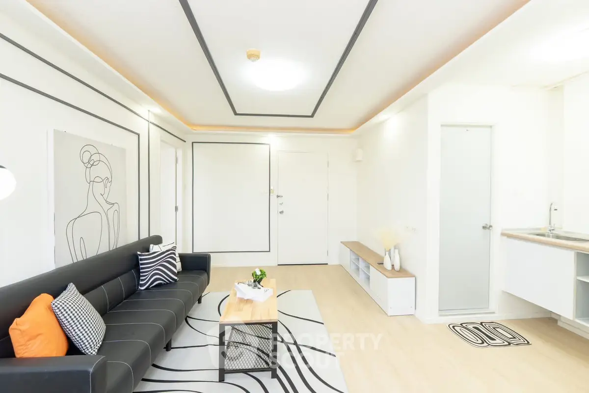 Modern living room with stylish decor and sleek furniture, featuring a black sofa and contemporary artwork.