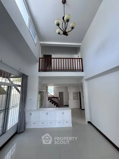 Spacious two-story living room with elegant chandelier and balcony view.