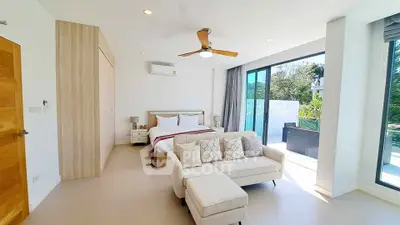Spacious bedroom with modern decor and large windows opening to a balcony with lush views.