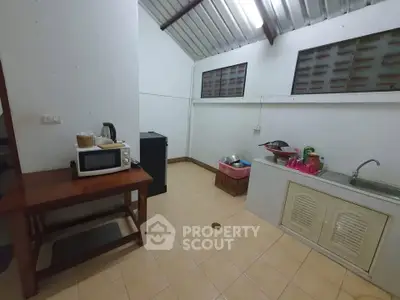 Cozy kitchen with high ceiling and essential appliances in a compact layout.