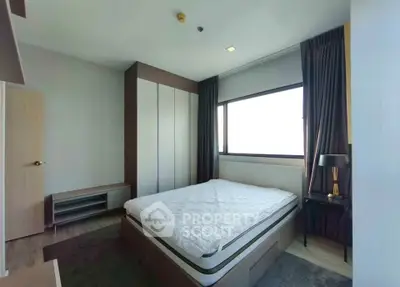 Modern bedroom with large window and stylish furnishings in a contemporary apartment.