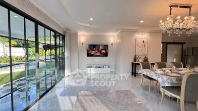 Luxurious open-plan living room with pool view and elegant dining area, featuring a chandelier and modern decor.