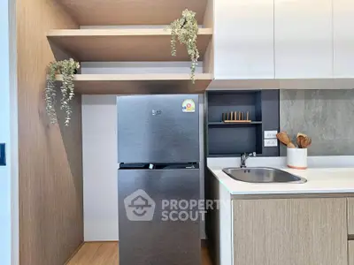 Modern kitchen with sleek fridge and stylish shelving in contemporary apartment.