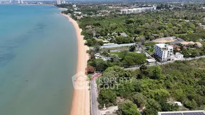 Stunning aerial view of beachfront property with lush greenery and oceanfront access, ideal for luxury real estate development.