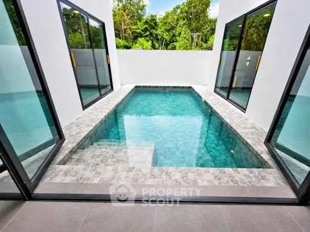Luxurious private pool with modern design and glass doors in a serene setting.