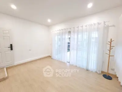Spacious empty living room with wooden flooring and large windows