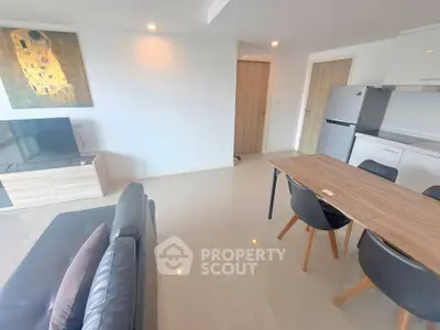 Modern living room with sleek furniture and open kitchen layout, featuring a stylish dining area and contemporary decor.