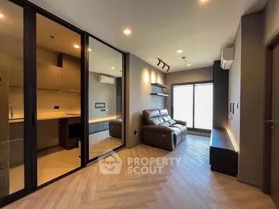 Modern living room with sleek design and large glass doors leading to kitchen.