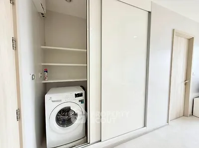 Modern laundry area with built-in washing machine and sliding door storage