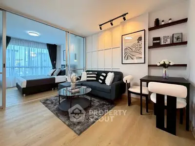 Modern studio apartment with stylish living area and cozy bedroom separated by glass partition.