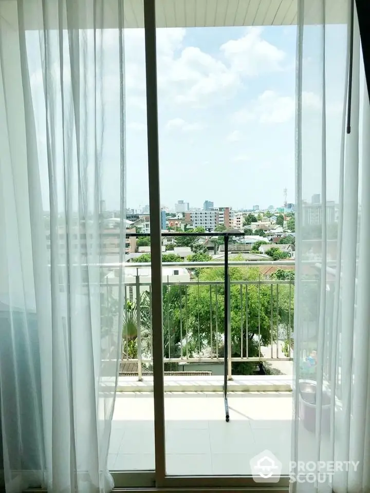 Bright balcony view with cityscape and greenery, perfect for relaxation and enjoying the outdoors.