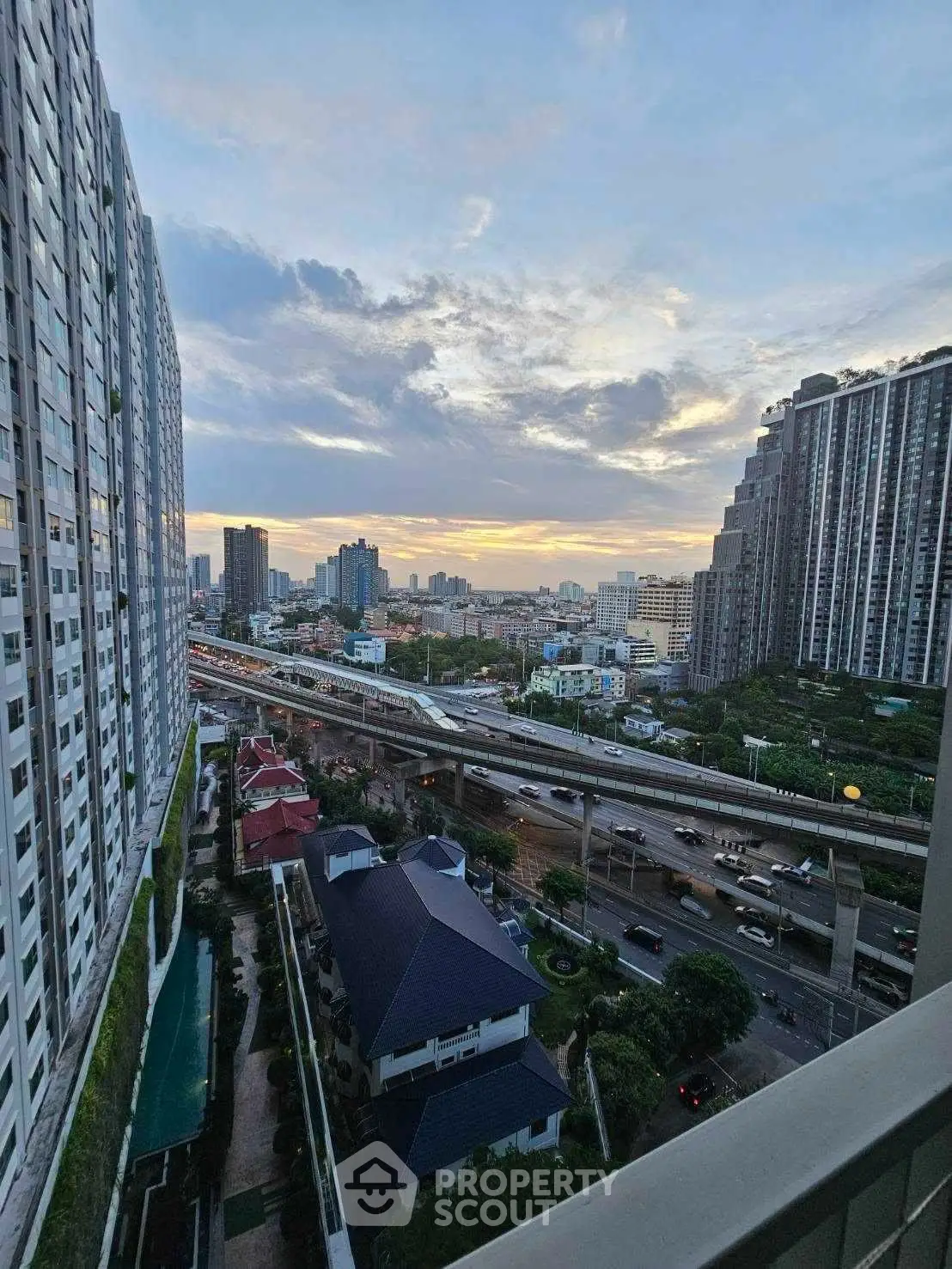 Stunning cityscape view from high-rise balcony at sunset, showcasing urban skyline and vibrant city life.