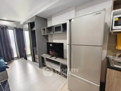 Modern apartment interior with sleek kitchen and spacious living area featuring large fridge and TV unit.
