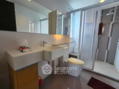Modern bathroom with sleek fixtures and glass shower enclosure in contemporary apartment.