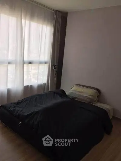 Cozy bedroom with large window and minimalist decor, perfect for relaxation.