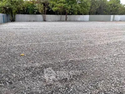Spacious gravel lot ideal for development, surrounded by trees and fencing, offering privacy and potential.