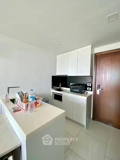 Modern compact kitchen with sleek white cabinets and appliances