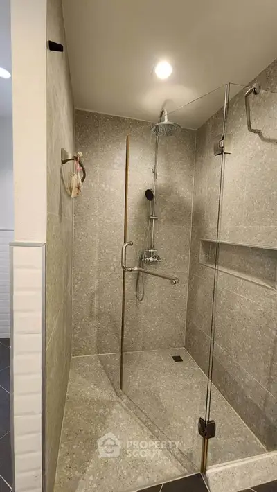 Modern bathroom with sleek glass shower enclosure and rainfall showerhead.