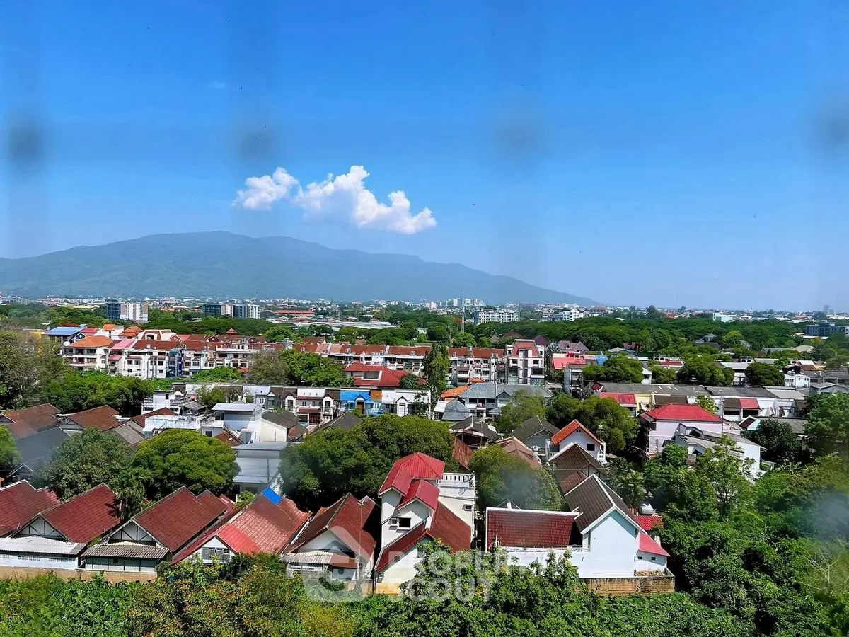 Scenic aerial view of suburban homes with mountain backdrop and clear blue sky.
