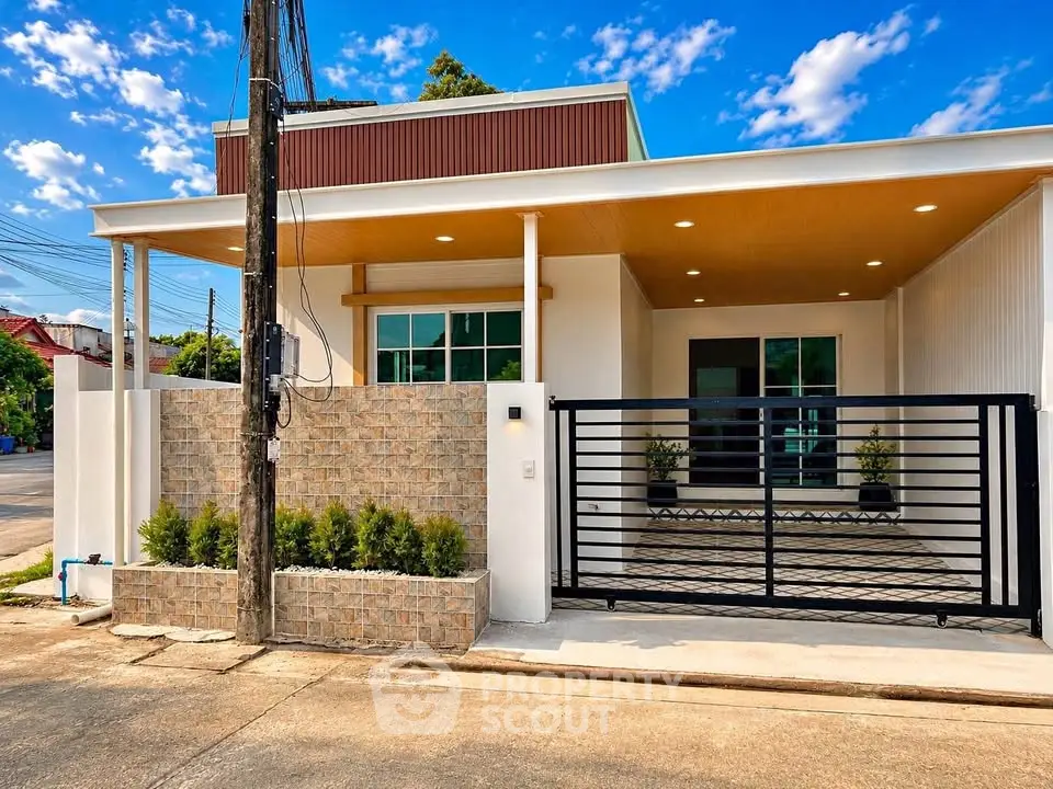 Modern single-story house with gated entrance and stylish facade under a clear blue sky.