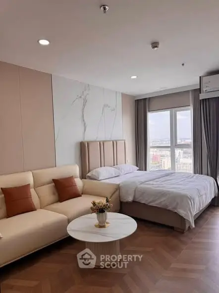 Modern studio apartment with cozy bed and stylish sofa, offering a stunning city view.
