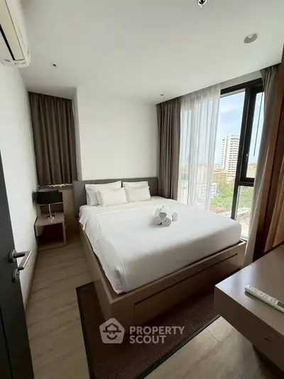 Modern bedroom with city view, featuring a cozy bed and elegant decor in a high-rise apartment.