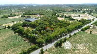 Expansive aerial view of lush green land with potential for development near urban skyline.