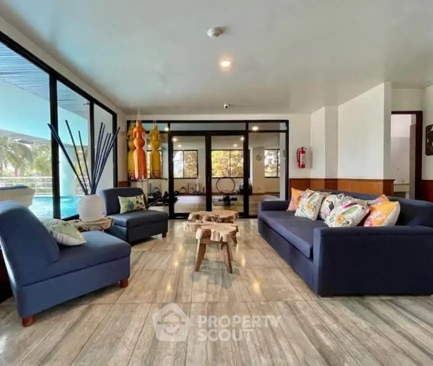 Spacious living room with modern decor and pool view, perfect for relaxation and entertaining.