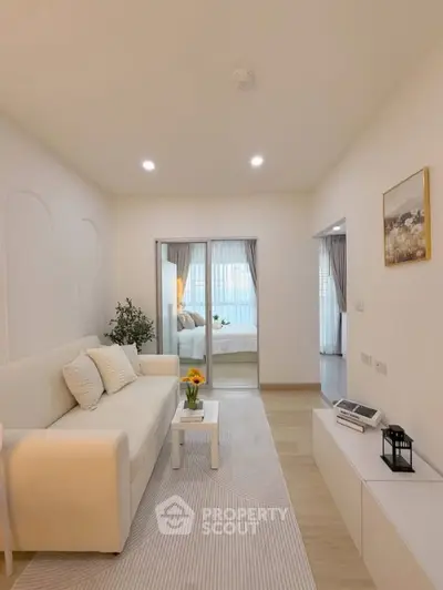 Modern living room with cozy white sofa and elegant decor leading to a bright bedroom.
