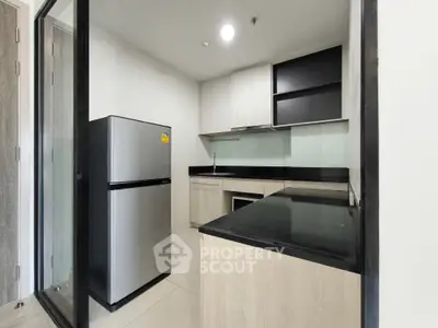 Modern kitchen with sleek design, featuring stainless steel fridge and ample counter space.