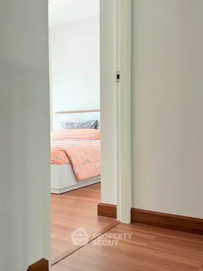 Cozy bedroom with wooden flooring and floral bedding, perfect for a peaceful retreat.