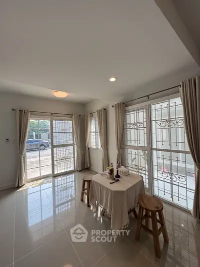 Bright and airy living room with large windows and elegant curtains, perfect for relaxation and entertaining.